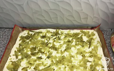 Натереть на терке соленые огурцы, отжать слегка и выложить на тесто.