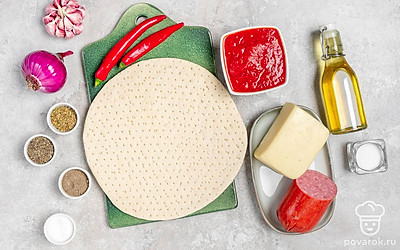 Откройте банку с томатами. Сыр натрите на терке или нарежьте слайсами. Разморозьте основу для пиццы на нижней полке холодильника. Лук и чеснок очистите. Чеснок пропустите через пресс, лук порежьте кольцами. Колбасу порежьте ломтиками. Перец чили помойте, аккуратно удалите плодоножку и семена, нарежьте тонкими колечками.