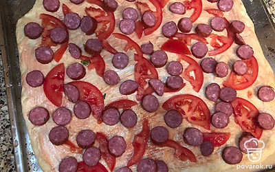 Сверху смазанного теста укладываем помидор, колбаски и отправляем в разогретую до 180 градусов духовку на 10 минут. 