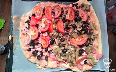 Готовим начинку. Консервированные шампиньоны обжариваем на сковороде с луком. Нарезаем ингредиенты: колбасу, ветчину, маслины, помидор. Натираем сыр на терке.
Раскатываем тесто, смазываем его томатным соусом, выкладываем начинку: колбасу, ветчину, шампиньоны с луком, помидорные дольки, маслины.
