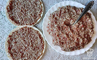 В фарш добавьте измельченный лук. По вкусу положите соль и черный перец молотый. Хорошо перемешайте. На каждый лавашный круг равномерно распределите по 100 грамм фарша до самых краев.