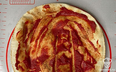 На питу выложите томатную пасту, распределите равномерно.
