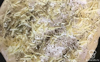 Раскатываем тесто, натираем сыр, смазываем тесто рикоттой и присыпаем половиной сыра. 