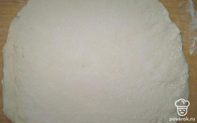 Слоёное бездрожжевое тесто достаньте из морозилки и подержите при комнатной температуре до размягчения. На это уйдёт от 20 до 35 минут в зависимости от температуры комнаты. На подпылённом мукой столе раскатайте пласт теста в круг по диаметру формы.