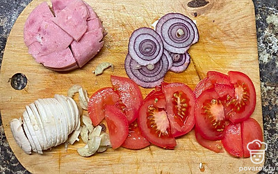 Нарежьте ломтиками ветчину, лук, грибы, помидор. Натрите сыр. 