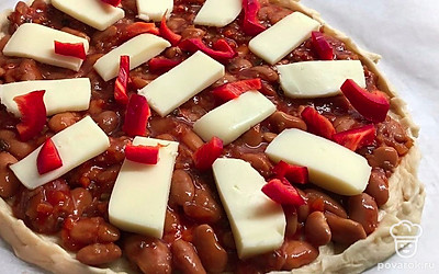 Нарежьте и разложите на пицце моцареллу. Порежьте красный перец. Разложите на пицце.