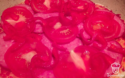 Разложите колбасу, помидоры, перец. Присыпьте поверх небольшим количеством сыра.