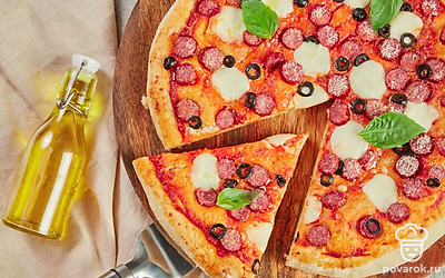 Горячую пиццу посыпьте тертым пармезаном и разложите на ней листочки базилика.