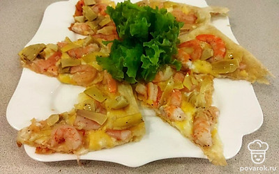 Когда пицца будет готова, разрежьте ее на порционные кусочки и выложите на тарелку. Для украшения используйте лист салата, также можно посыпать измельченной зеленью сверху.