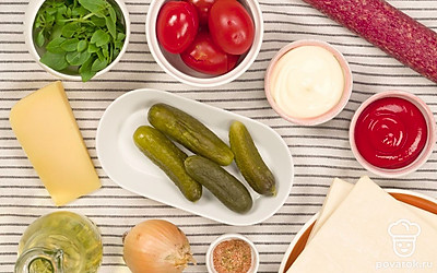 Упаковку со слоеным тестом разрежьте, но тесто из нее не вынимайте. Оставьте размораживаться при комнатной температуре. С соленых помидоров снимите кожицу. Репчатый лук очистите. В глубокой мисочке смешайте кетчуп и майонез. Приготовьте противень. Включите духовку на 250 градусов. Зелень базилика промойте и разделите на листики.