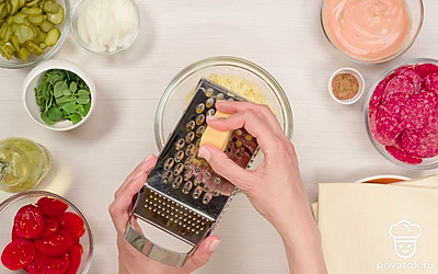 Измельчите продукты. Колбасу нарежьте соломкой, четвертинками или кружочками. Лук нарежьте полукольцами. Сыр натрите на средней терке. Огурцы и помидоры нарежьте кружочками.