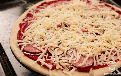 Сделайте из теста тонкий диск, раскатывая его до диаметра 25-30 см. Смажьте основу томатной пастой и выложите на противень, разложите шампиньоны и салями. Сверху равномерно посыпьте тертые сыры и отправьте в духовку на 15 минут.