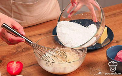 Приготовьте тесто. В глубокой миске смешайте воду, яйцо и майонез. Хорошо перемешайте венчиком и постепенно начинайте вводить муку с разрыхлителем. Замесите мягкое тесто. Оно должно немного липнуть к рукам. Накройте получившуюся основу для пиццы на майонезе полотенцем и оставьте его отдыхать на несколько минут.