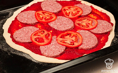 Из полученного теста сделайте в диск диаметром 25-30 см, положите его на противень и смажьте томатным соусом или пастой. На тесто положите помидоры, салями и полейте оливковым маслом. Посыпьте начинку сырами. Отправьте пиццу в духовку на 15 минут.