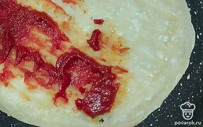 На разогретую сухую сковороду выложите готовую замороженную лепешку. Обжаривайте с одной стороны. Переверните и смажьте томатной пастой.