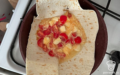 Поставьте сковороду на газ. Положите в сковородку лаваш и поверх лаваша разложите смесь. Заверните лаваш с краев, в форме конвертика. 
Жарьте без масла, на одной стороне. Томите 4 минуты. Переверните, накройте крышкой и ждите еще минут 6-7.