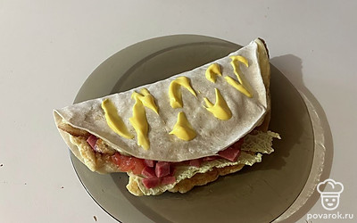 Лепешку подавайте к столу, дополнительно украсив сырным соусом.