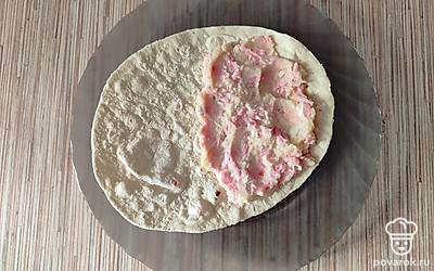 На одну сторону круглого лаваша выложите приготовленную начинку. 