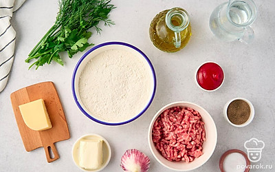 Просейте муку в глубокую миску. Помойте и почистите чеснок. Ополосните укроп и петрушку, промокните их бумажными салфетками. Отделите листочки зелени от стеблей. Подготовьте терку, еще одну миску, скалку, чистое тканевое полотенце, сковороду и блюдо для подачи. 