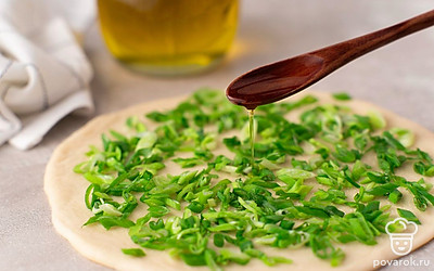 Мелко нарежьте зеленый лук. Полейте тесто 1 ч.л. растительного масла и насыпьте сверху немного лука.