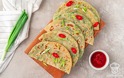 Разрежьте каждую лепешку на 2 части, посыпьте резаным луком и перцем чили. Подавайте с острым соусом.