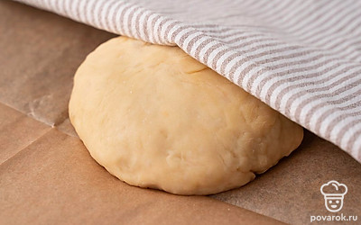 Придайте поднявшемуся тесту форму шара, переложите его на противень с пергаментной бумагой. Прикройте шар из теста полотенцем и оставьте на 15 минут.