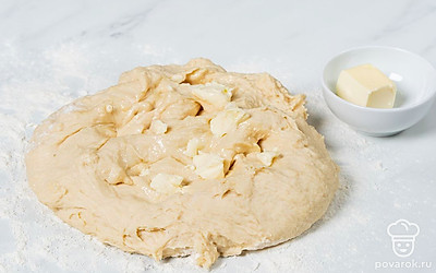 Частями добавьте в тесто сливочное масло, хорошенько вымешивайте после каждого кусочка. Готовое тесто скатайте в шар и положите в миску. Накройте пищевой пленкой и оставьте в теплом месте на 1,5 часа.