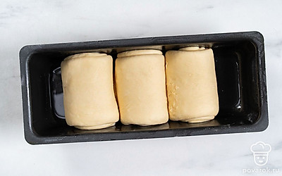 Разогрейте духовку до 180℃. Смажьте форму для запекания растительным маслом. Выложите в нее рулетики теста. Накройте форму пищевой пленкой и оставьте на один час в теплом месте. Взбейте венчиком куриное яйцо с молоком и смажьте им сверху поднявшееся тесто. Отправьте форму в духовку на 30 минут.