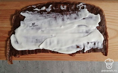 Блин разрежьте пополам. Каждую половинку смажьте сметанным соусом. 