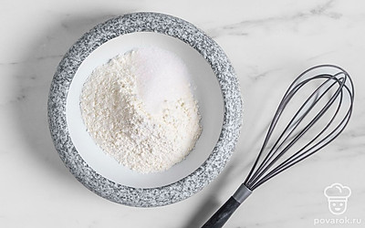 Всыпьте муку в подготовленную глубокую миску. Для начала просейте ее через мелкое ситечко. Благодаря этому она насытится кислородом, и готовые булочки получатся пышнее. Всыпьте немного сахара к муке.