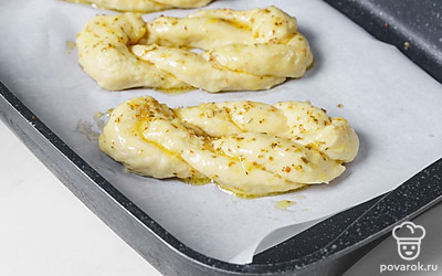 Включите духовку разогреваться до 180 градусов. Когда «узелки» поднимутся, смажьте их глазурью с помощью силиконовой кисточки или салфетки. Поместите заготовки в разогретую духовку и выпекайте примерно 15-20 минут. Дайте булочкам постоять на противне еще 5 минут, после чего переложите на сервировочную тарелку.