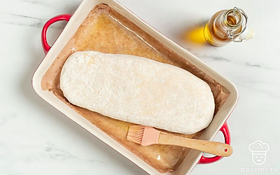 Пергаментную бумагу на противне смажьте оливковым маслом. С помощью пленки переложите батон на противень с бумагой, пленку уберите