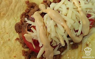 На сырную лепешку выкладываем фарш, помидор, сыр и поливаем соусом. 