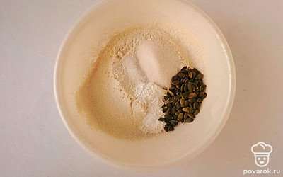 Просейте муку в глубокую емкость, соедините с солью, сахаром, разрыхлителем и семечками тыквы. Добавьте сухие ингредиенты в емкость с кефиром. Тщательно перемешайте.