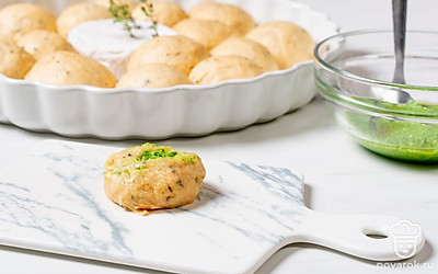 Камамбер выложите на противень и воткните в него веточки тимьяна. Сбрызните вином. Тесто обомните и разделите на 20 кусочков. Скатайте из них шарики, приплюсните. Выложите в центр небольшое количество песто и заверните края наверх, чтобы получилась круглая заготовка. Положите рядом с сыром швом вниз. Сделайте так со всем тестом.