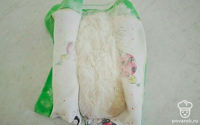 По истечении времени стол припылите мукой, выложите тесто, с помощью полотенца сделайте бортики, подложив бутылки из-под воды. Тесто накройте полотенцем и оставьте в таком виде на 45 минут. Затем на противень, застеленный пергаментом, переложите тесто и отправьте будущую чиабатту в духовку, разогретую до 240 °С, выпекаться в течение 15 минут. После чего снизьте температуру выпекания до 200 °С и готовьте мучное изделие еще 20 минут до румяной корочки.