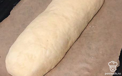 Далее необходимо достать тесто из миски и сформировать из него батон. Я это делаю методом скручивания в рулет, немного приминая серединку и края. Выложите сформированный батон на противень, застеленный пергаментом.