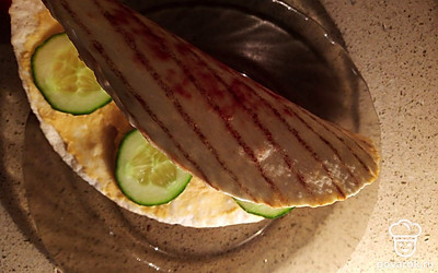 Сверните лепешку вдвое, украсьте внутри ломтиками огурцов.