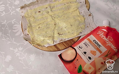 На четверть лаваша выложите чайную ложку сырного соуса и равномерно распределите его по лавашу.
