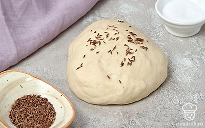 Начните готовить лепешку. В миске смешайте рассол, сахар, соду, тмин и 3 ст. л. растительного масла. Постепенно всыпайте муку, постоянно помешивая лопаткой. Затем вымесите тесто руками — оно должно стать мягким и при этом не липким.