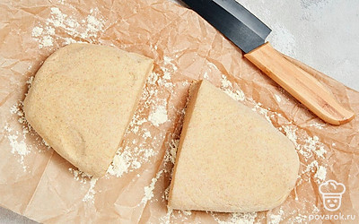 Начните приготовление чиабатты. На рабочую поверхность выложите лист пергаментной бумаги, посыпьте его кукурузной мукой. Тесто извлеките из миски и разделите на равные части. После этого выложите кусочки теста на пергамент, накройте их полотенцем и оставьте еще на 40-50 минут.