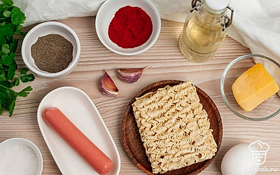 Приготовьте необходимые ингредиенты. Достаньте лапшу быстрого приготовления из упаковки. Снимите обертку с сосиски. Почистите чеснок. Зелень помойте и обсушите.