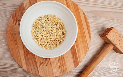 Лапшу положите на доску и измельчите молоточком.