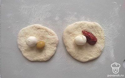 Разделите тесто на 15 частей, раскатайте каждую часть в лепешку, во внутрь которой положите моцареллу с вяленым томатом или маслиной. Придайте форму шарика.