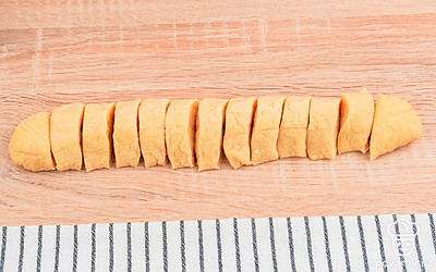 Подготовьте чистую поверхность для работы с тестом. Снимите пищевую пленку с теста и придайте ему форму колбаски. Затем разрежьте тесто поперек на кусочки одинаковой толщины.