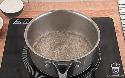 Чтобы приготовить сахарный сироп для баурсаков, возьмите сотейник и влейте в него воду. Добавьте сахар и размешайте. Кипятите жидкость до появления более вязкого состояния.