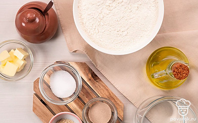 Приготовьте опару: смешайте воду, дрожжи, сахар и соль, дайте дрожжам подняться. Просейте муку или взбейте ее блендером для насыщения кислородом. Застелите противни для выпечки пергаментной бумагой. Подготовьте чистое полотенце и большую емкость для теста.