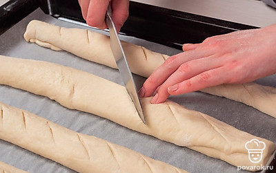 Сформируйте багеты. Разрежьте тесто на 4 равные части, каждую раскатайте и сверните колбаской. Переложите их на противень и оставьте в теплом месте на 15 минут.