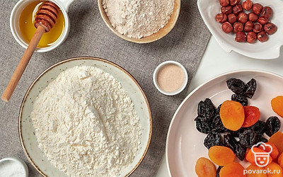 Сухофрукты зелейте кипятком, оставьте на 2-3 минуты, затем жидкость слейте, обсушите сухофрукты и нарежьте небольшими кусочками. Просейте муку в миску подходящего размера для замешивания теста. Приготовьте противень для выпечки и посыпьте его мукой.
