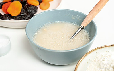 Сделайте медовую опару. В емкость небольшого размера налейте воду чуть теплее комнатной температуры, растворите в ней мед, добавьте сухие дрожжи, тщательно размешайте.